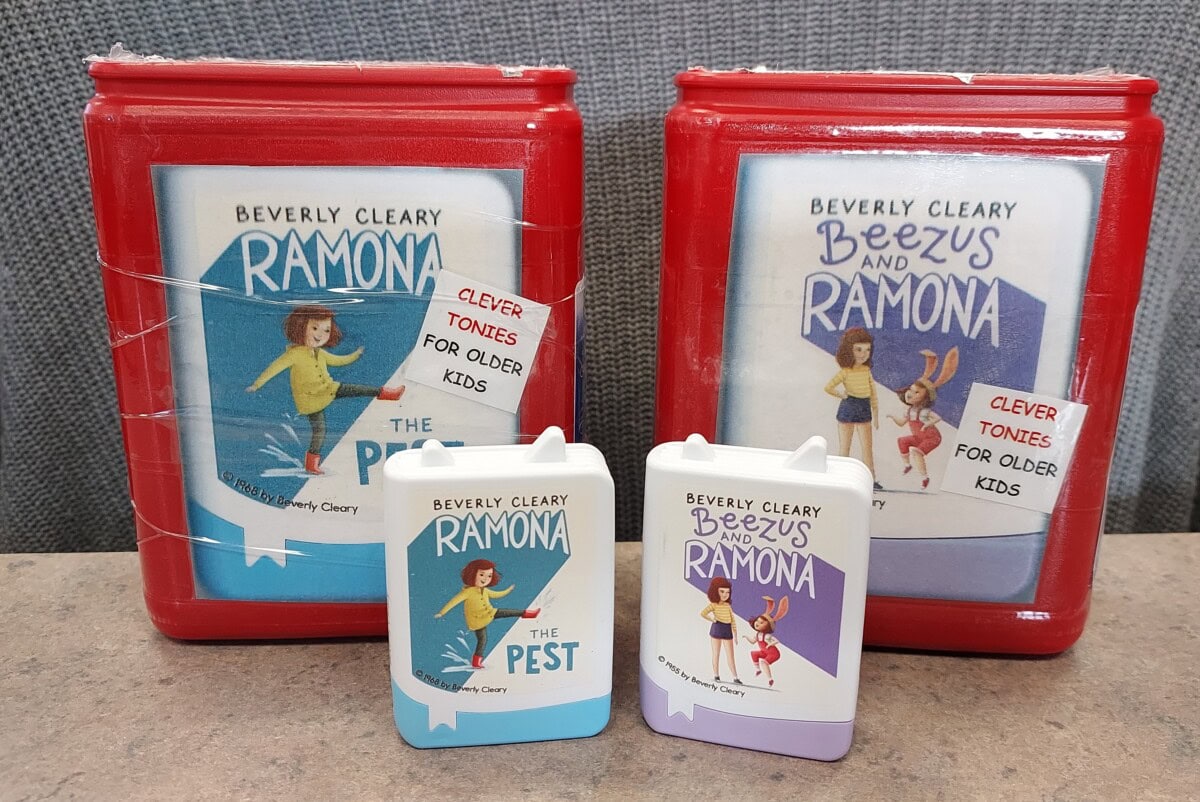 Two red rectangular audiobook cases and their matching white cassette tapes for Ramona the Pest and Beezus and Ramona by Beverly Cleary, both labeled Clever Tonies for older kids, displayed on a table.