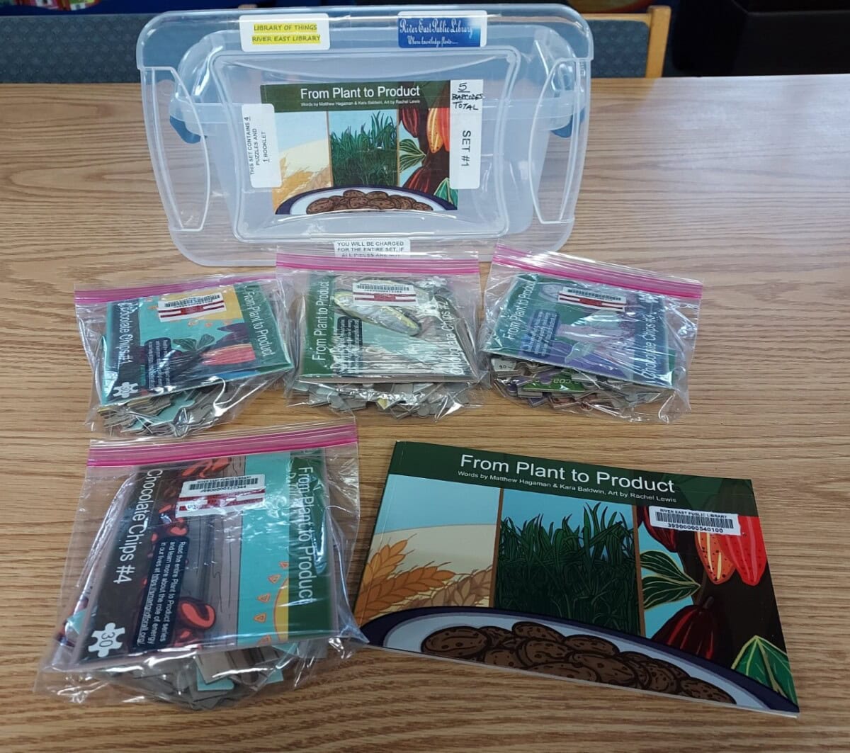 A clear plastic box labeled “From Plant to Product” contains several ziplock bags, each with educational materials and seed packets, all arranged neatly on a wooden table. Booklets with plant illustrations are also included.