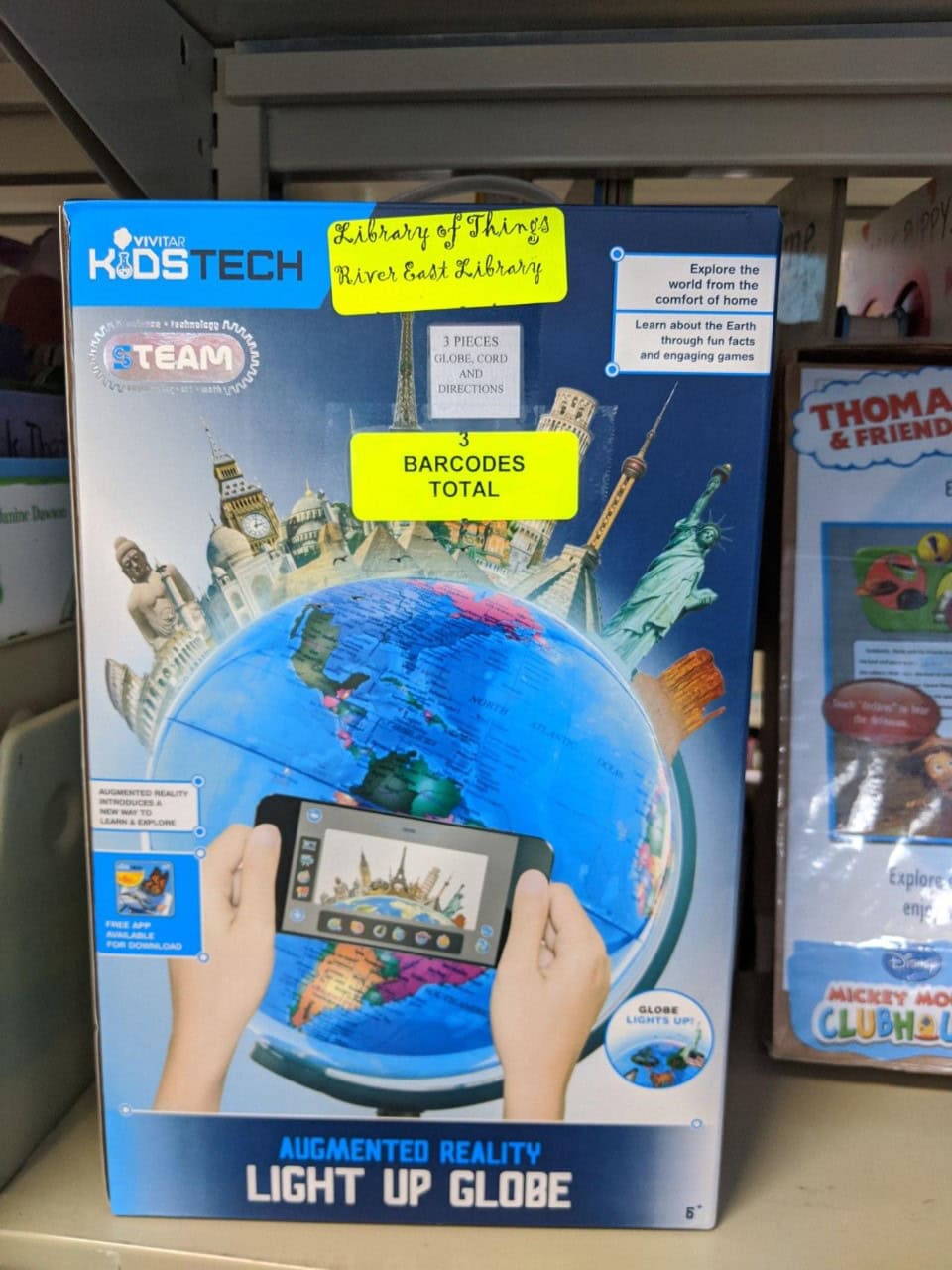 A box labeled Augmented Reality Light Up Globe shows hands holding a phone over a globe with world landmarks and icons popping up. Sticky notes say 3 barcodes total and Rivers East Library at the top.