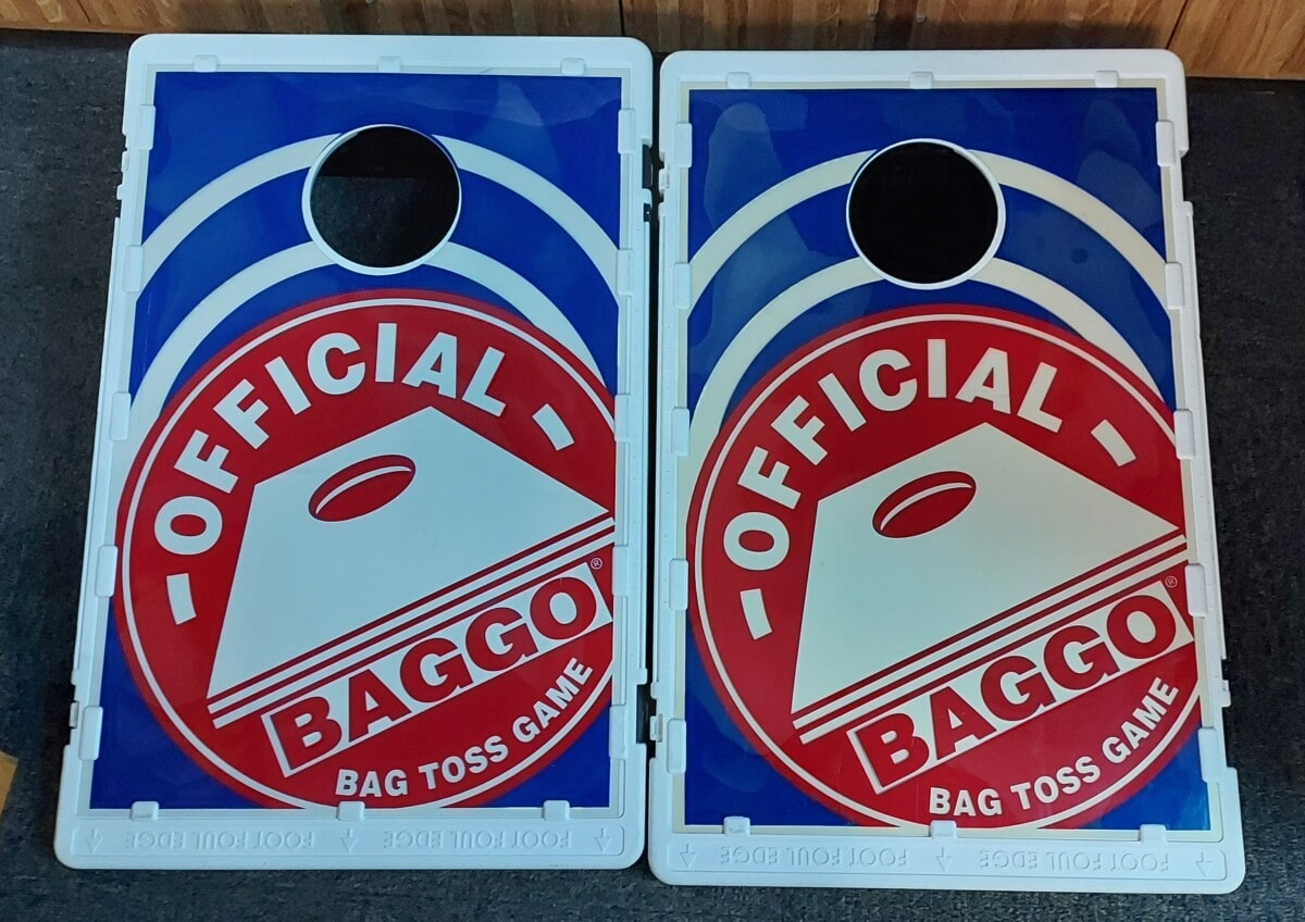 Two rectangular blue and white cornhole boards with large red and white circular Official BAGGO Bag Toss Game logos. Each board has a black hole near the top for tossing bags. The boards are set side by side.