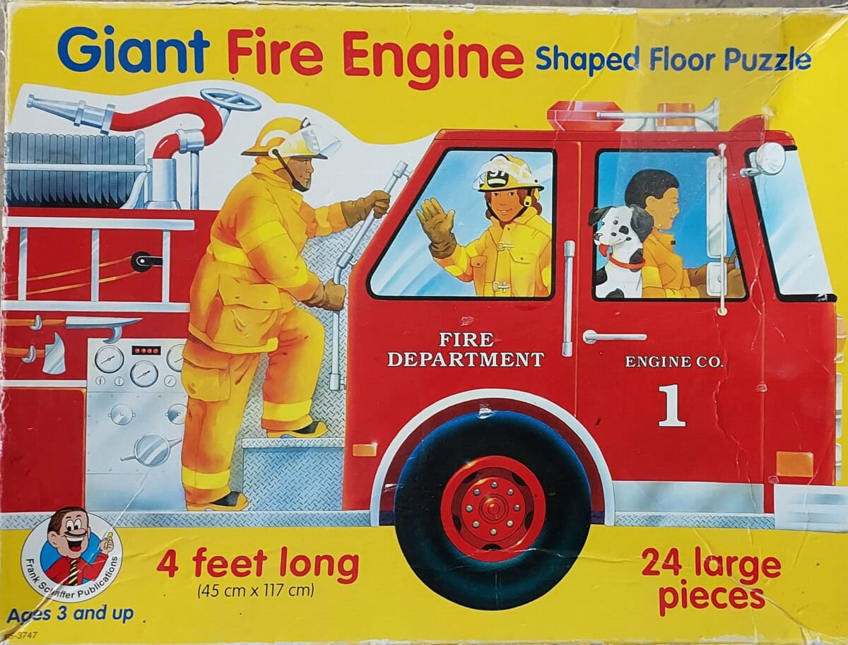 A colorful puzzle box shows firefighters and a Dalmatian in and around a red fire engine. The box reads Giant Fire Engine Shaped Floor Puzzle, 4 feet long, and 24 large pieces. For ages 3 and up.