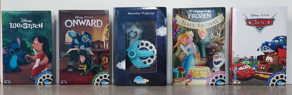 Five Disney-themed storybook covers are displayed upright in a row: Lilo & Stitch, Onward, a Moonlite projector, Frozen: Elsa’s Birthday, and Cars, all on a brown surface against a white background.