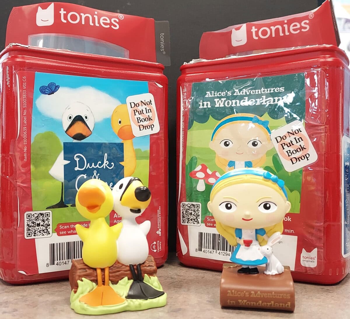 Two Tonies audio figure sets: one of a duck and a goose in front of a Duck & Goose box, and one of Alice and a white rabbit in front of an Alices Adventures in Wonderland box.