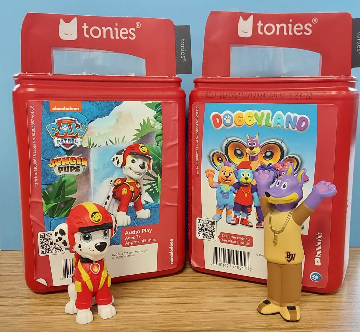 Two red Tonies audio play boxes are shown. The left box features Paw Patrols Marshall figure in front of a jungle scene. The right box displays a purple Doggyland character figure with arms raised in front of a colorful backdrop.