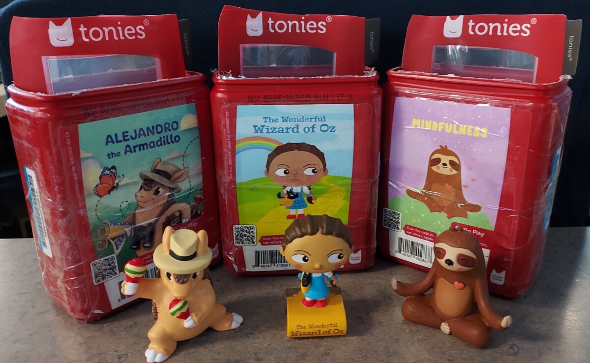 Three Tonies audio figure boxes are shown: Alejandro the Armadillo, The Wonderful Wizard of Oz, and Mindfulness, each with a matching figure—a cowboy armadillo, Dorothy, and a meditating sloth—in front.