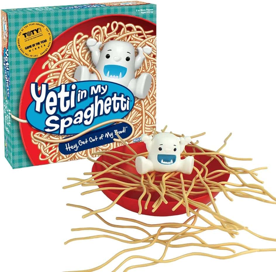 The Yeti in My Spaghetti game box and setup, featuring a white yeti figure sitting on a pile of yellow plastic spaghetti strands in a red bowl. The game’s colorful packaging is visible in the background.